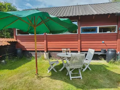 a table and chairs under a green umbrella in a yard at Kathøje in Lemvig