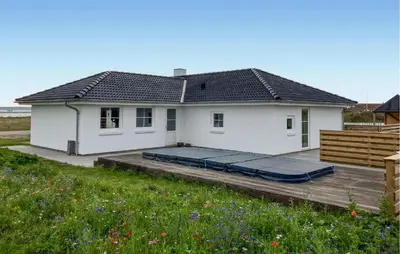 a small white house with a deck and a house at Cozy Home In Struer With Sauna in Struer