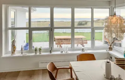 a dining room with large windows and a table at Cozy Home In Struer With Sauna in Struer