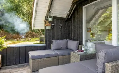 a patio with a couch and a table and a window at Fjord Views And Spa By Limfjorden in Roslev
