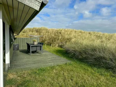a table on a deck next to a house at Bright Holiday Home Close To Sea Near Blokhus in Blokhus