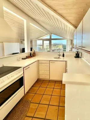 a large kitchen with white counters and a large window at Bright Holiday Home Close To Sea Near Blokhus in Blokhus