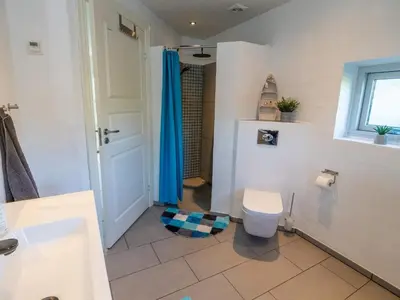 a bathroom with a toilet and a blue shower curtain at 4 star holiday home in Hanstholm in Hanstholm