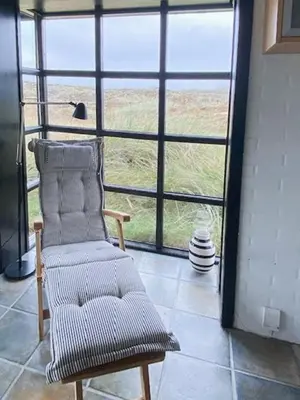 a chair in a room with a large window at Summerhouse By The Heath Near The North Sea in Snedsted