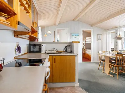 a kitchen with wooden cabinets and a dining room at Holiday Home Gisa - 500m from the sea by Interhome in Thisted