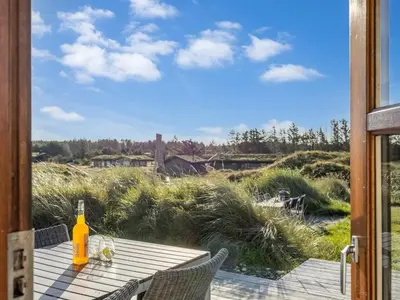 a table with a bottle of wine sitting on a patio at Holiday Home Sigbritt - 750m from the sea by Interhome in Løkken