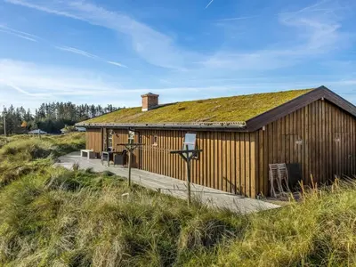 a building with a grass roof with a wooden deck at Holiday Home Sigbritt - 750m from the sea by Interhome in Løkken