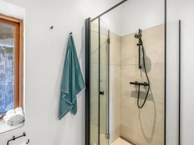 a bathroom with a shower with a glass door at Holiday Home Sigbritt - 750m from the sea by Interhome in Løkken