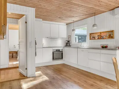 a kitchen with white cabinets and a wooden ceiling at Holiday Home Ingamaj - 4km from the sea by Interhome in Brovst