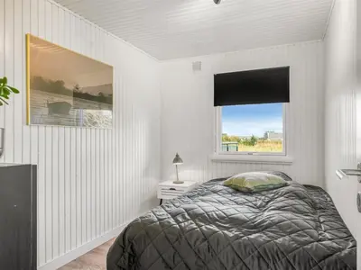 a white bedroom with a bed and a window at Holiday Home Sarika - 500m from the sea by Interhome in Fjerritslev
