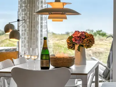 a table with a bottle of wine and two glasses at Holiday Home Adelbrand - 1km from the sea by Interhome in Blokhus