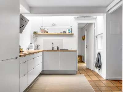 a kitchen with white cabinets and a tile floor at Holiday Home Adelbrand - 1km from the sea by Interhome in Blokhus