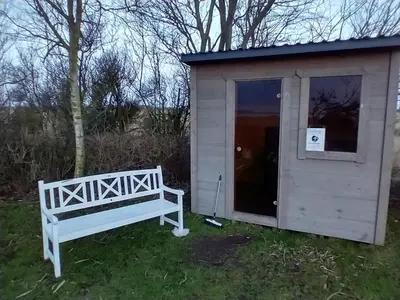 a white shed with a bench next to it at Apartment with water views in Fjerritslev
