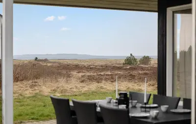 a table with chairs and a view of a field at Cozy Home In Løgstør With Sauna in Løgstør