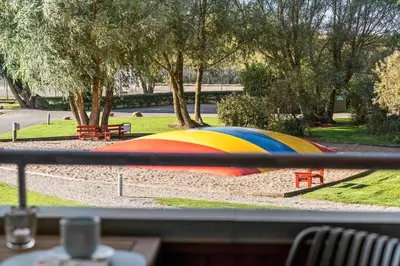 a rainbow colored umbrella sitting in a park at G346-Lemvig-Vinkelhagevej-46 in Lemvig