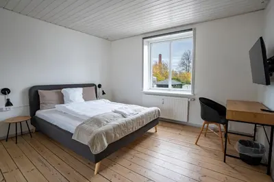 a bedroom with a bed and a desk and a window at City Apartments in Holstebro