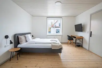 a bedroom with a bed and a desk and a window at City Apartments in Holstebro