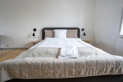 a bedroom with a large white bed with two lamps at City Apartments in Holstebro