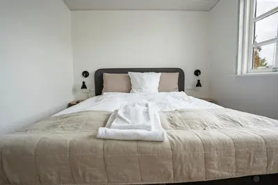 a white bedroom with a large bed with two pillows at City Apartments in Holstebro