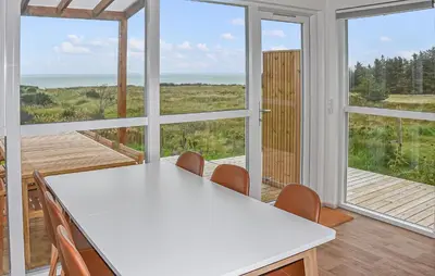 a kitchen with a white table and chairs and windows at Gorgeous Home In Hanstholm With House Sea View in Hanstholm