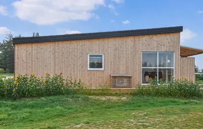 a wooden house with a large window in a field at Gorgeous Home In Hanstholm With House Sea View in Hanstholm