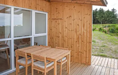 a wooden table and chairs on a wooden deck at Nice Home In Hanstholm With House Sea View in Hanstholm