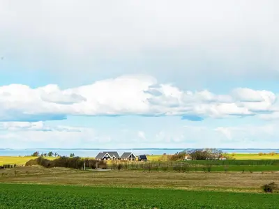 a house in a field with the ocean in the background at 4 star holiday home in Ranum in Ranum