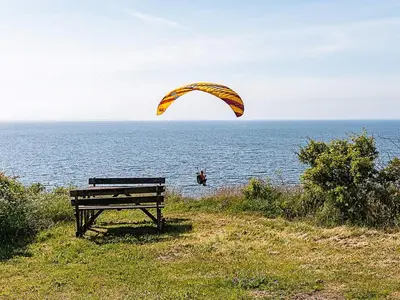 a person flying a parachute over the water with a bench at 4 star holiday home in Ranum in Ranum
