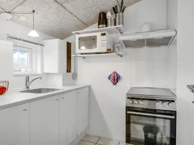 a white kitchen with a sink and a microwave at Holiday Home Sylvana - 75m from the sea by Interhome in Thisted