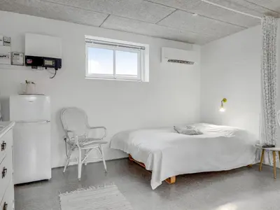 a white bedroom with a bed and a chair at Holiday Home Sylvana - 75m from the sea by Interhome in Thisted