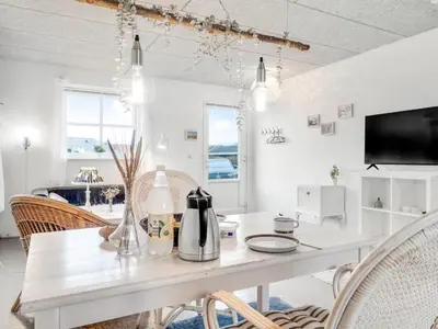 a white dining room with a table and chairs at Holiday Home Sylvana - 75m from the sea by Interhome in Thisted