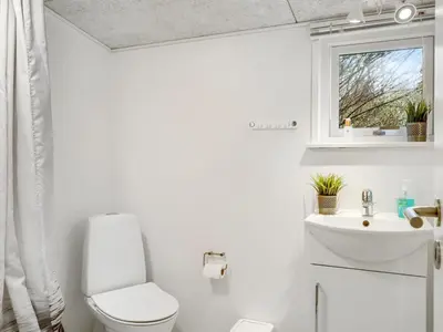 a bathroom with a toilet and a sink and a window at Holiday Home Tekla - 75m from the sea by Interhome in Thisted