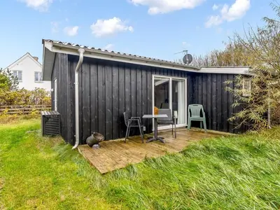 a black shed with a table on a wooden deck at Holiday Home Tekla - 75m from the sea by Interhome in Thisted
