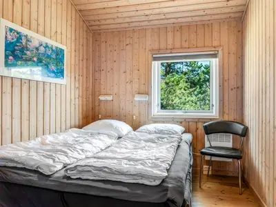 a bed in a room with a chair and a window at Holiday Home Melita - 2km from the sea by Interhome in Blokhus