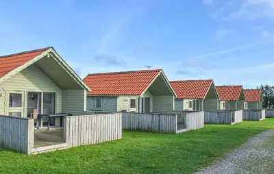 a row of houses with red roofs behind a fence at Beautiful Home In Hanstholm With House A Panoramic View in Hanstholm