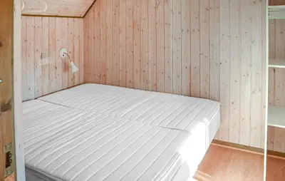 a white bed in a room with wooden walls at Beautiful Home In Hanstholm With House A Panoramic View in Hanstholm