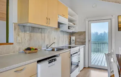 a kitchen with white cabinets and a sink and a balcony at Lovely Home In Hanstholm With Private Swimming Pool, Can Be Inside Or Outside in Hanstholm