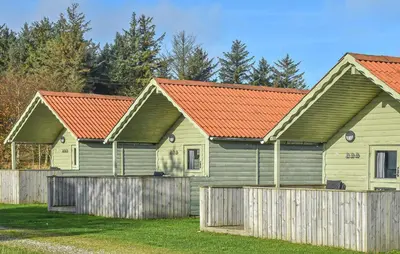 three houses with red roofs behind a fence at 2 Bedroom Beautiful Home In Hanstholm in Hanstholm