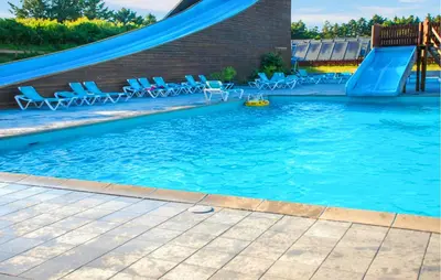 a swimming pool with a slide and chairs in it at Stunning Home In Hanstholm With Outdoor Swimming Pool in Hanstholm