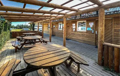 a patio with tables and benches on a wooden deck at Stunning Home In Hanstholm With Outdoor Swimming Pool in Hanstholm
