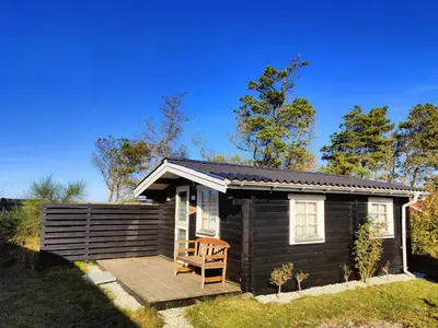 a small wooden cabin with a wooden deck at Cozy Cottage Close To Thy National Park in Thisted