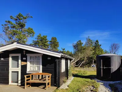 a black shed with a bench in front of it at Cozy Cottage Close To Thy National Park in Thisted
