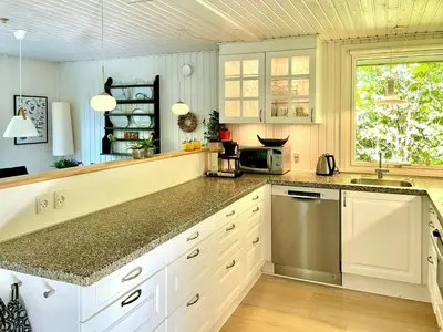 a kitchen with white cabinets and a counter top at Nature Retreat With Fjord Views Near Spøttrup in Spottrup