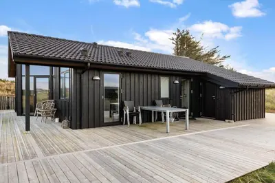 a black house with a table on a deck at 1071-Thisted-Gravsesvej-30 in Klitmøller