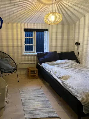 a bedroom with a bed and a window and a chandelier at Log Cabin With Hot Tub And Fjord View in Viborg
