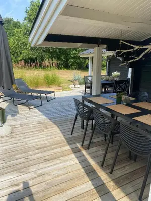 a patio with a table and chairs and an umbrella at Log Cabin With Hot Tub And Fjord View in Viborg