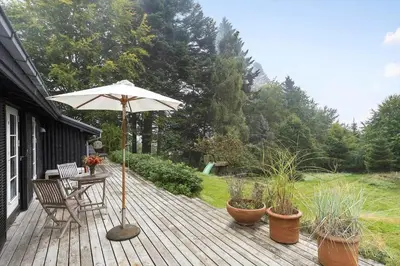 a wooden deck with a table and an umbrella at JB238-Brovst-Baunehojvej-37 in Brovst