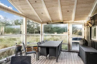 a screened in porch with a table and chairs at BL1141-Saltum-Faarup-Klitvej-2-A in Saltum