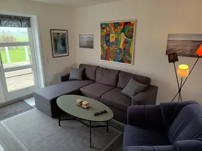 a living room with a couch and a table at Bolig ved hav og fjord in Thyholm