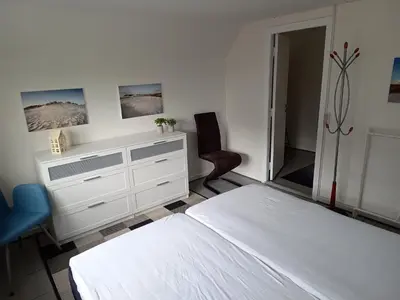 a white bedroom with a bed and a dresser at Bolig ved hav og fjord in Thyholm